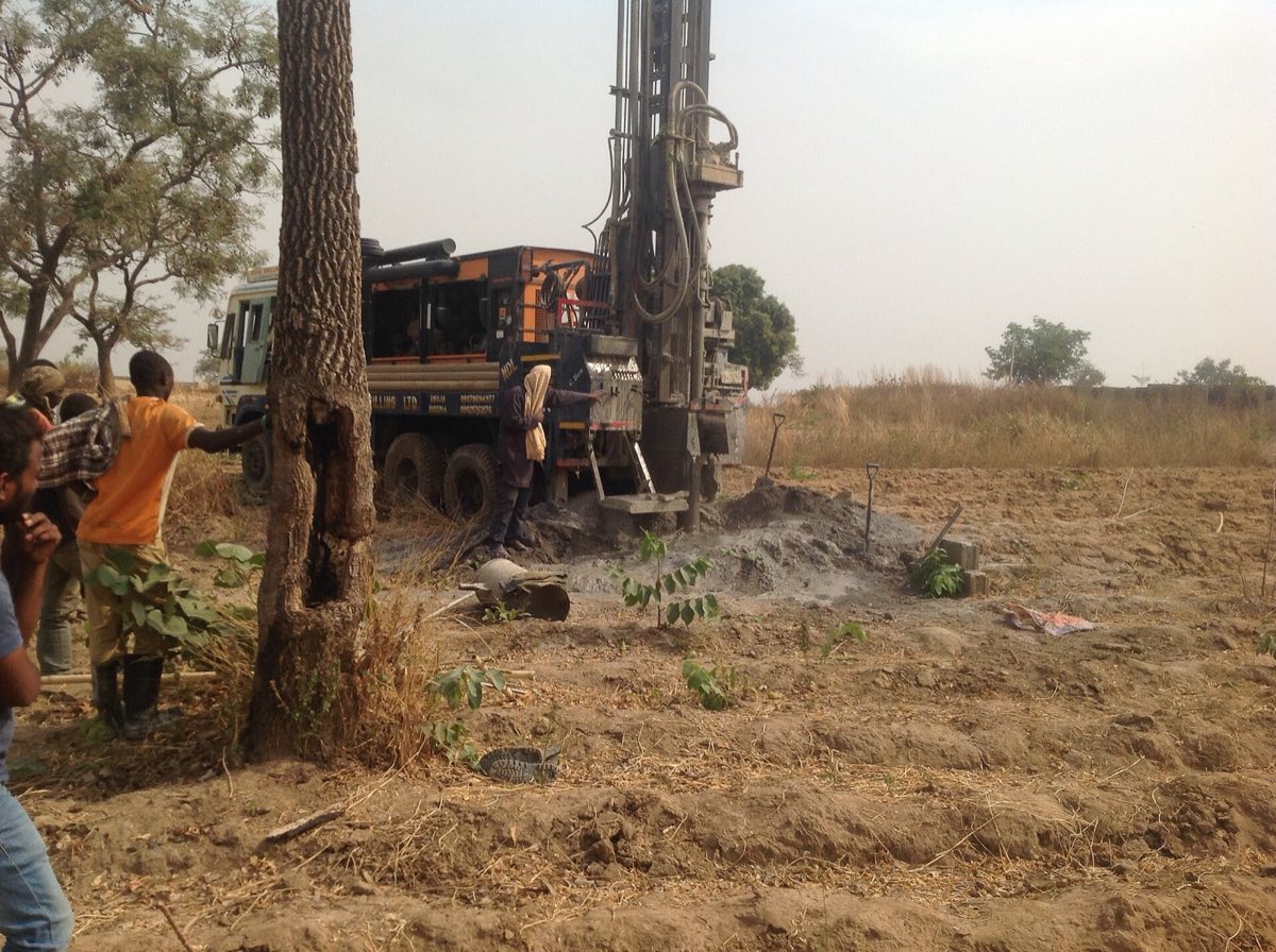 Drilling crew working beside a truck-mounted rig at a borehole site