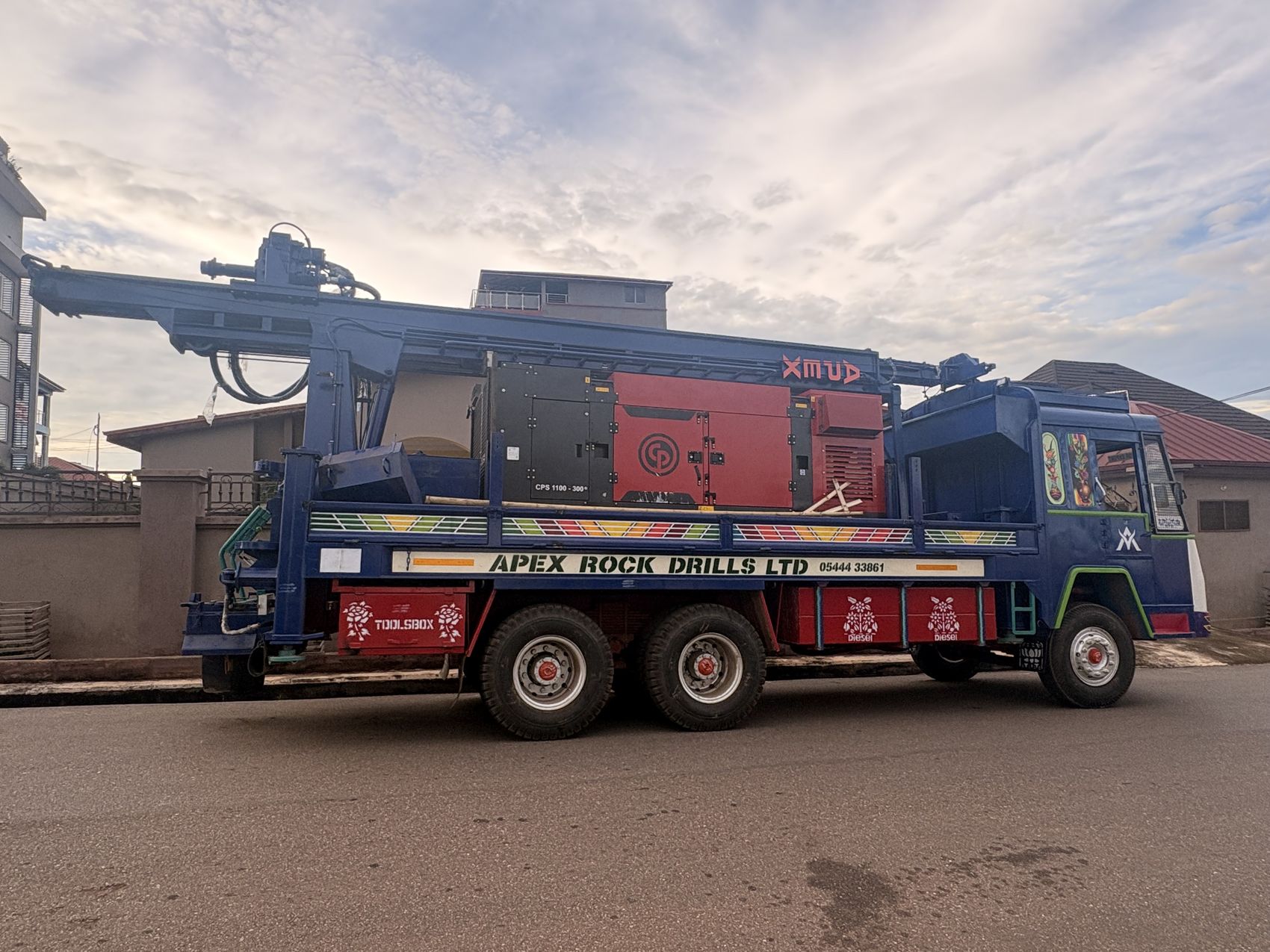An Apex Rock Drills truck-mounted rig, liveried with the company name, on the road to a job site