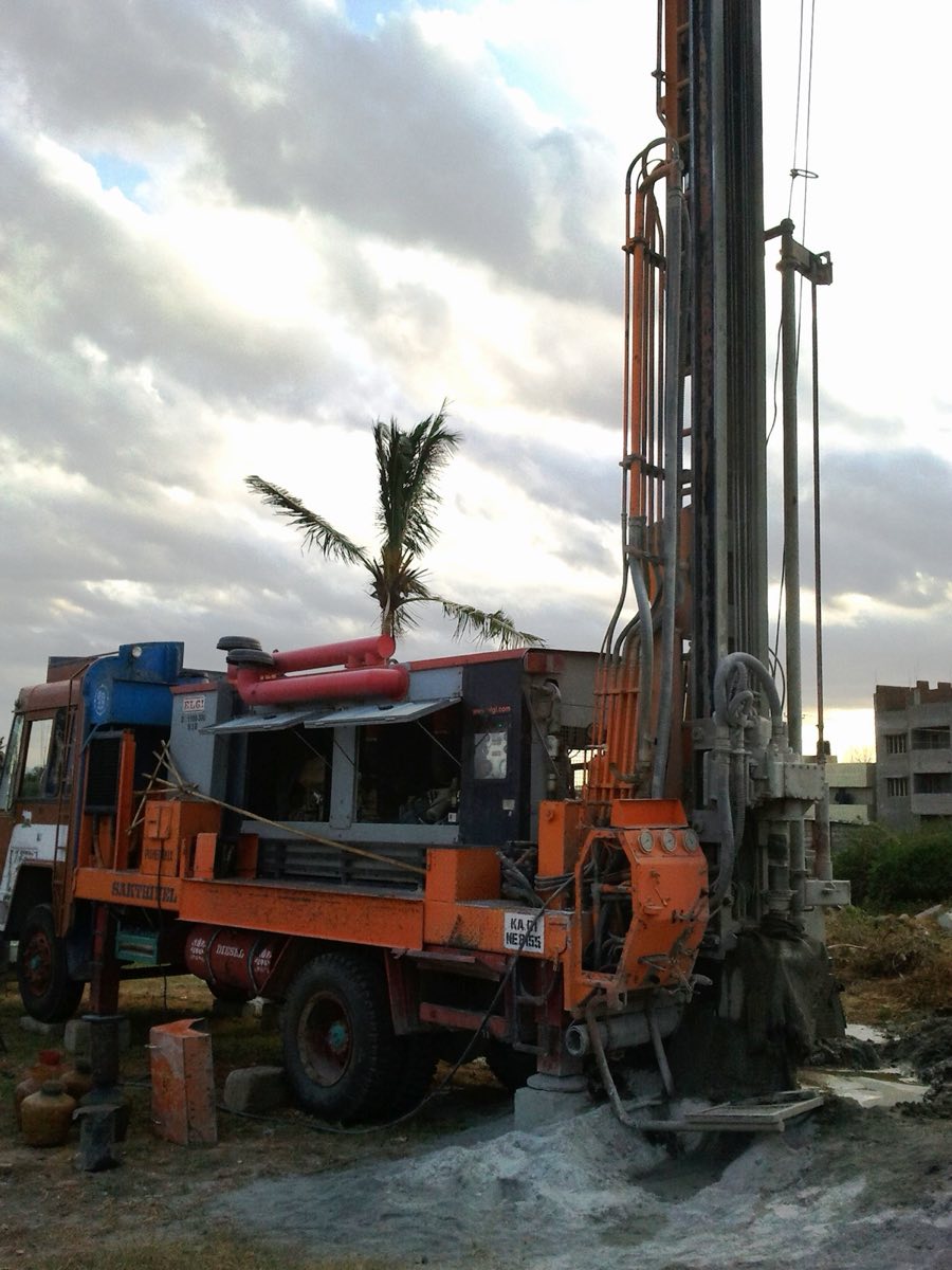 Truck-mounted water borehole rig drilling on site, mast raised